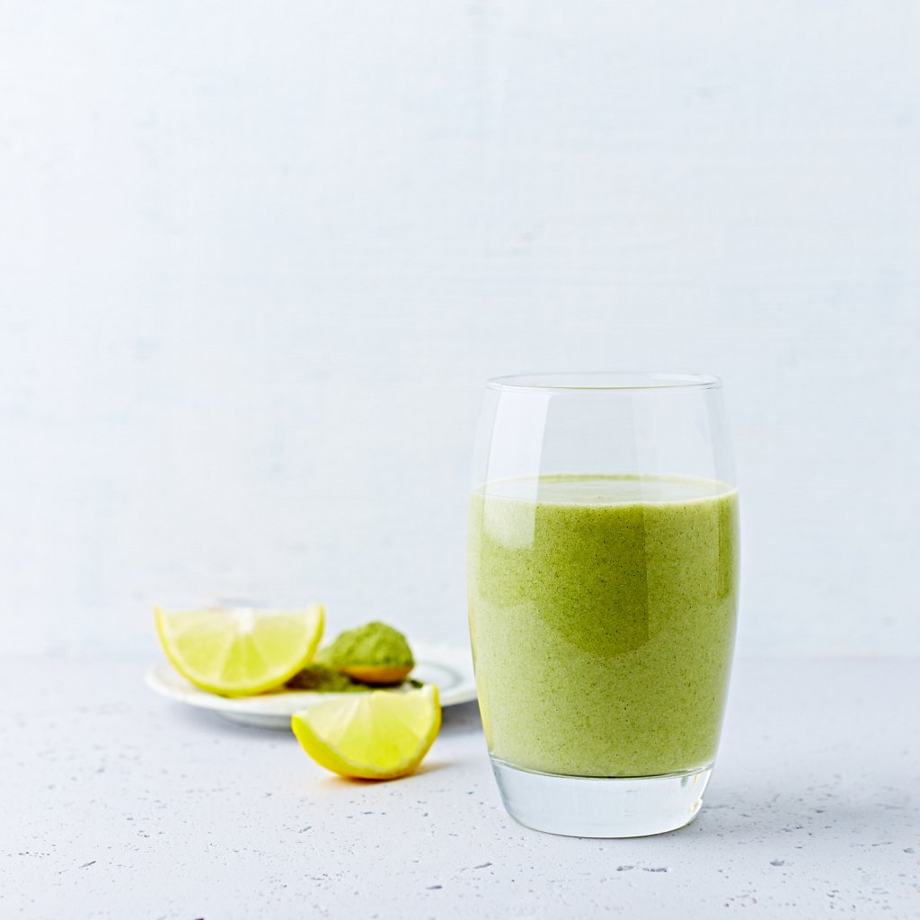Avocado-banana smoothie made with almond milk and young barley grass. Copy space. Healthy diet. Natural food