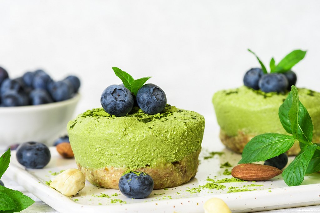 homemade raw matcha powder cakes with fresh berries, mint, nuts. healthy vegan food concept